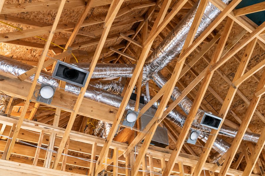 Insulated flexible air ducts installed between attic roof trusses